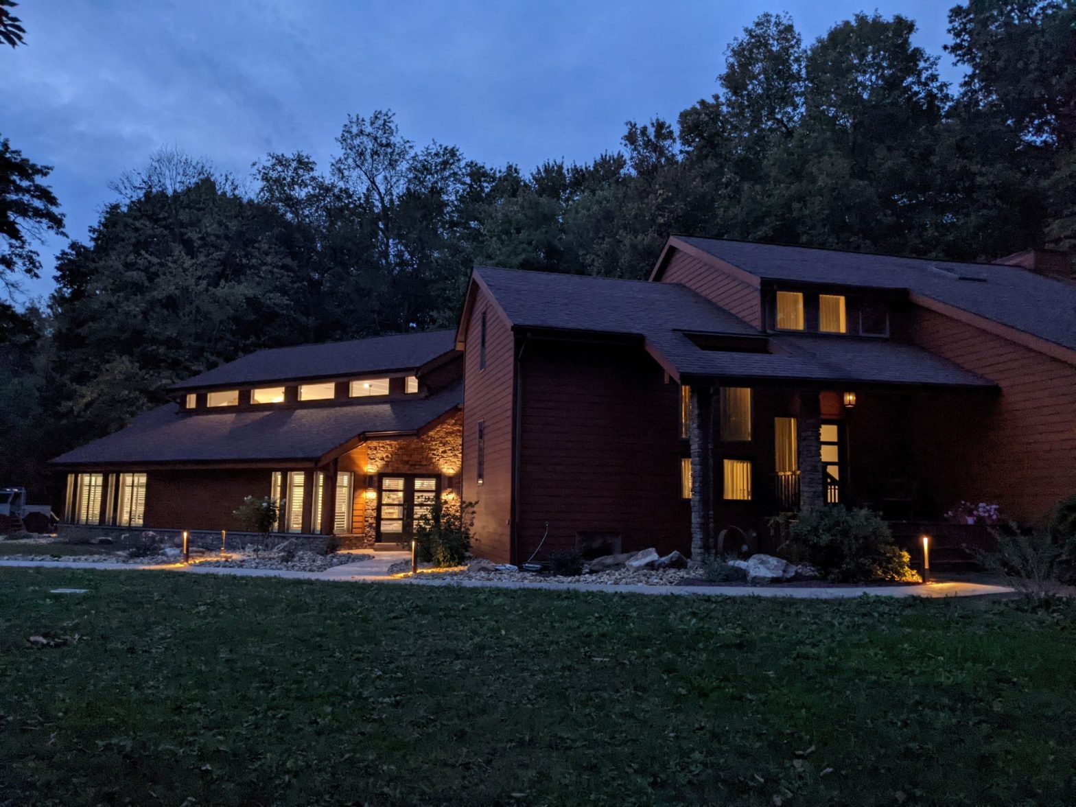 Exterior view of residential contemporary pool house addition to existing home at dusk